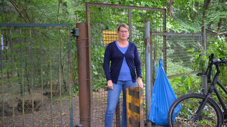 Ramona Nowak steht vor dem Gitter, das seit Kurzem den Zugang in den Wald bei Rheitlage von der Straße Am Schwalbenufer verhindert.