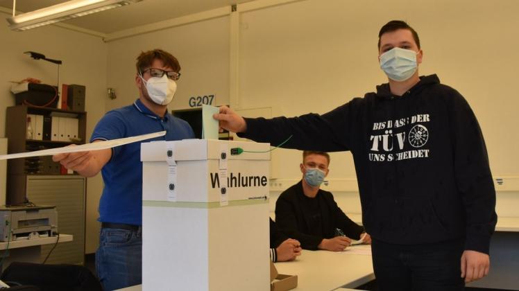 Die Schüler der BBS II in Delmenhorst haben für den Ernstfall geprobt: Max Dahm (l.) und David Tischke (Mitte) schauen ganz genau hin, dass der Wahlzettel von Pierre Nitsch korrekt in der Urne landet.