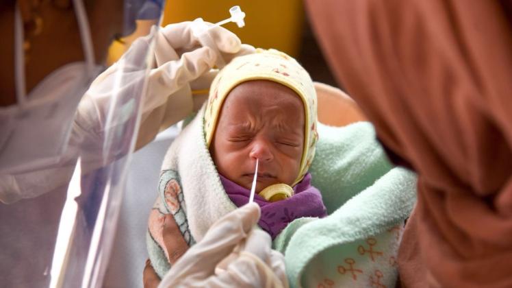 Eine Medizinerin entnimmt einem Baby in einem Krankenhaus einen Nasenabstrich für einen Corona-Test.