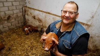 Bauer Jürgen Schächter mit einem Ferkel. Für 60 Euro im Monat gehört einem eines seiner Rotbunten Husumer Schweine bis es dann auch auf dem Teller landet.