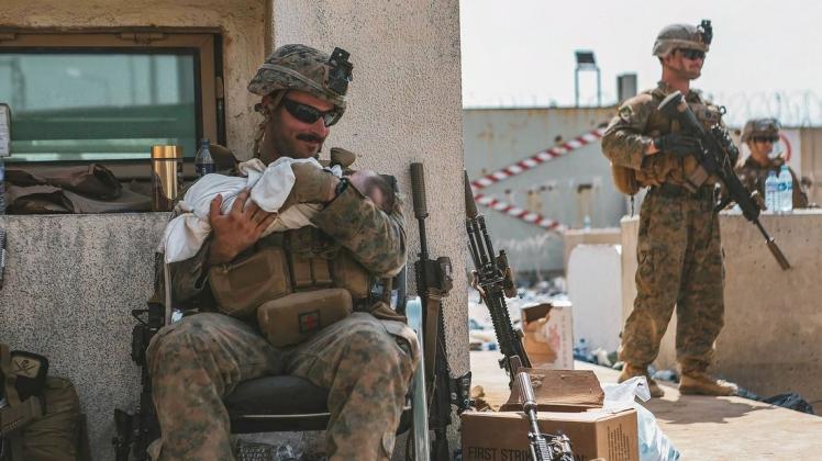 Zärtlichkeit im Kriegsgebiet: Ein US-Marine beruhigt ein Kleinkind während einer Evakuierung am Hamid Karzai International Airport. Auch ein Baby versorgten die Soldaten vorübergehend.