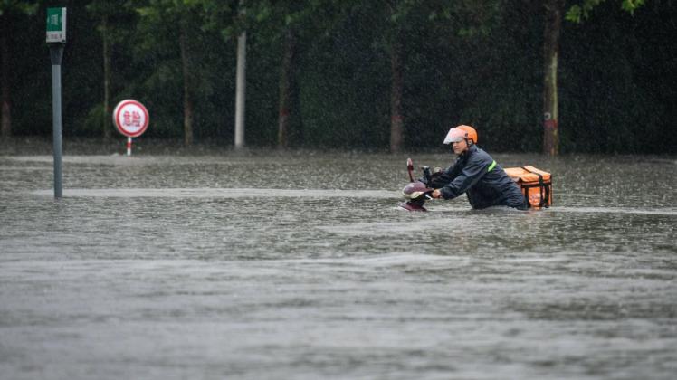 Ein Essenslieferant in Zhengzhou in Zentralchina kämpft sich mit einem Roller durch das Hochwasser. Mehrere Menschen starben in den Fluten.