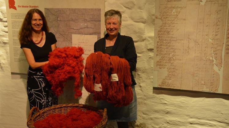 Bramscher Rot einst und jetzt: Während Museumsleiterin Kerstin Schumann (links) Flocken im aktuellen Bramscher Rot  präsentiert, zeigt Volkskundlerin Rose Scholl Wolle, die nach Originalproben aus dem 18. Jahrhundert gefärbt wurde.