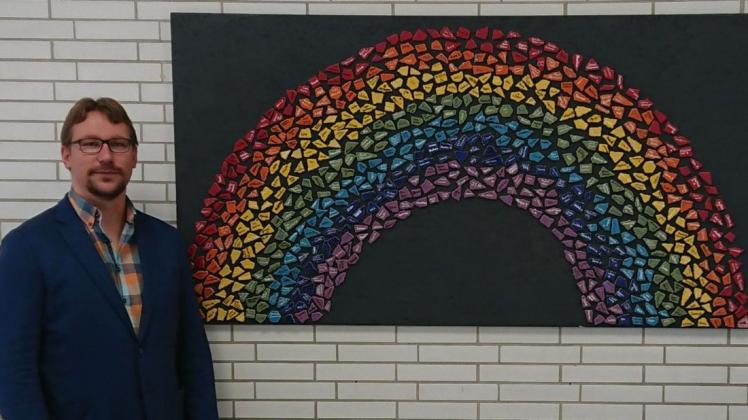 Schulleiter Alexander Willeke vor einem Regenbogenbild-Bild der Schüler. Jeder Mosaikstein steht für einen Schüler - laut Willeke ein Ausdruck für den Zusammenhalt in der Johannesschule in Meppen.