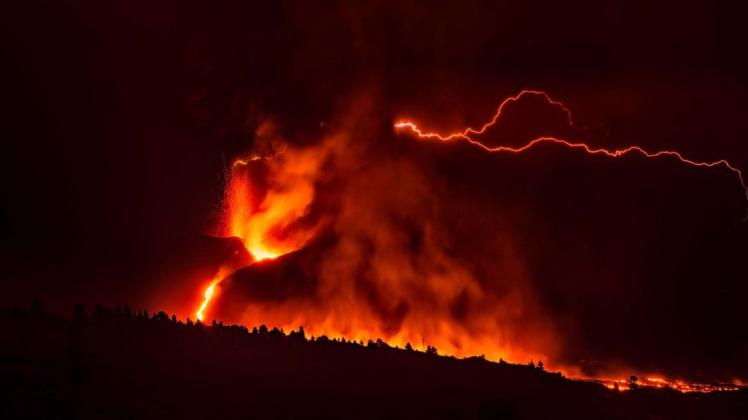 Ein vulkanischer Blitz über dem Vulkan Cumbre Vieja ist trotz des dichten, dunklen Rauchs, der aus dem Krater aufsteigt, von weitem sichtbar. Durch die Reibung zwischen der Asche und dem vom Vulkan ausgestoßenen Material werden Ionen freigesetzt, die die so genannten vulkanischen Blitze erzeugen – ein sehr häufiges Phänomen bei Vulkanausbrüchen.