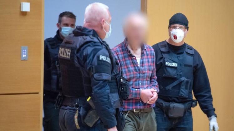 Der Angeklagte, Vater des Attentäters von Hanau 2019,  wird von einem Polizisten in den Verhandlungssaal geführt.