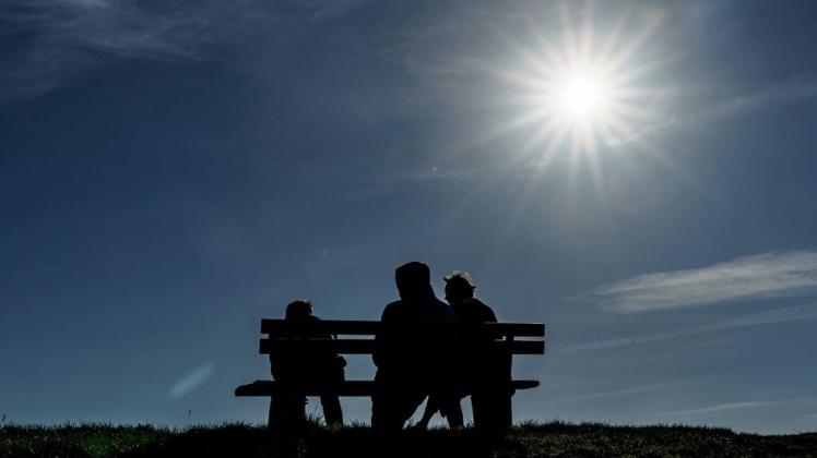 Eine Familie genießt den goldenen Oktobertag im Norden bei Sonnenschein auf einem Deich.