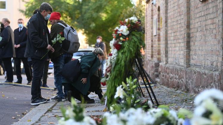 Menschen gedenken vor der Synagoge in Halle/Saale den Opfern des Halle-Attentats.