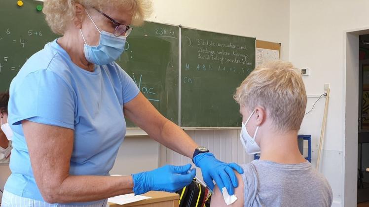 Justin lässt sich in seiner Schule von Krankenschwester Heide Anguria gegen Corona impfen. Sie ist mit einer Kollegin von den Johannitern in die Wisser-Schule gekommen.