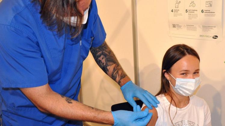 Ein Arzt verabreicht einer jungen Frau eine Spritze mit einem Vakzin gegen das Coroina-Virus.