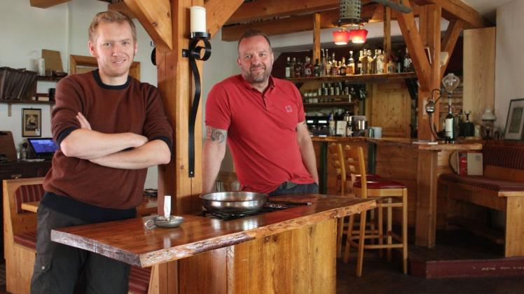 Die Inhaber vom Restaurant „Zum Oberförster“ in Seehof, Bastian Maukel (l.) und Ronny Woisin, haben viele Ideen für ihre Gastronomie, darunter auch der selbstgebaute Flambierer aus Holz.