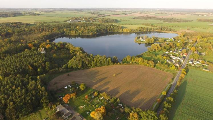 Luftbild mit See im Hintergrund: Auf dieser derzeit noch landwirtschaftlich genutzten Fläche soll ab Herbst die "Wohn- und Feriensiedlung Tramser See" entstehen.
