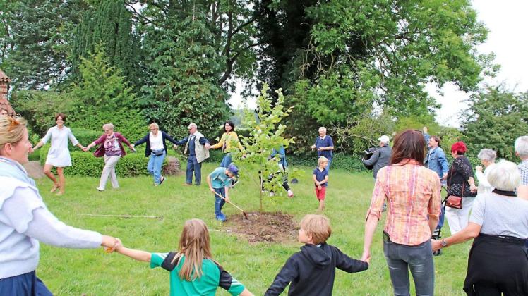 Als die Linde eingepflanzt ist, fassen sich die Menschen an die Hände und tanzen und singen zum Akkordeonspiel von Peter Franz aus Bützow im großen Kreis um den Baum herum.