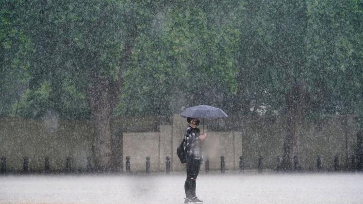 Eine Frau in London schützt sich mit einem Schirm vor dem starken Regen. Eine Frau in London schützt sich mit einem Schirm vor dem starken Regen.