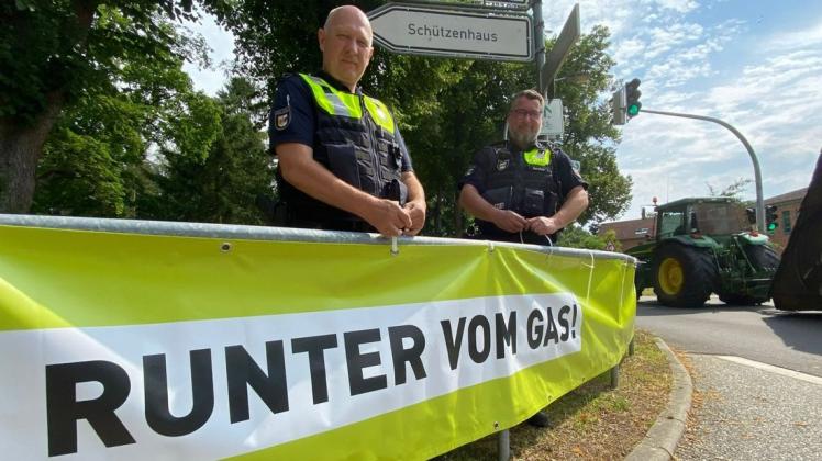 Auch im Bereich der Rehnaer Schule befestigten die Polizisten Olaf Jürgens und Frank Dornfeld (r.) das Banner „Runter vom Gas!“