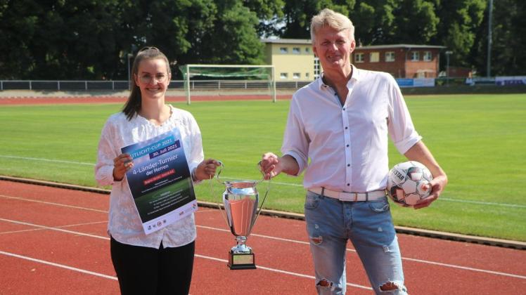 Christin Drescher, Vertrieb/Marketing der Stadtwerke, und Veritas-Präsident Arndt Leeke präsentieren Pokal und Plakat des Flutlicht-Cups 2021.