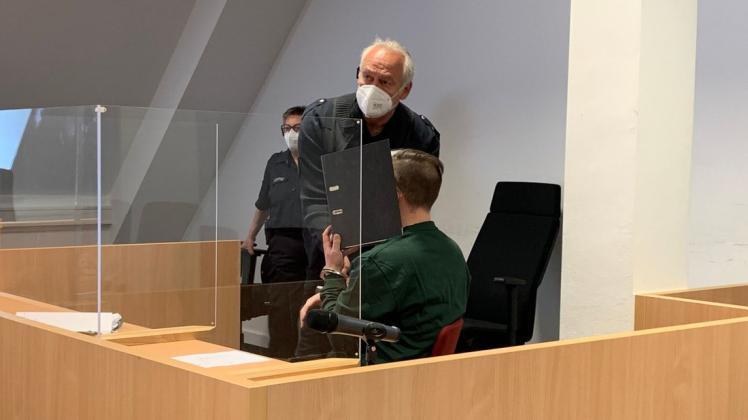 Der Angeklagte Till K. vor dem Lübecker Landgericht. Ein Justizvollzugsbeamter nimmt ihm die Handschellen ab.