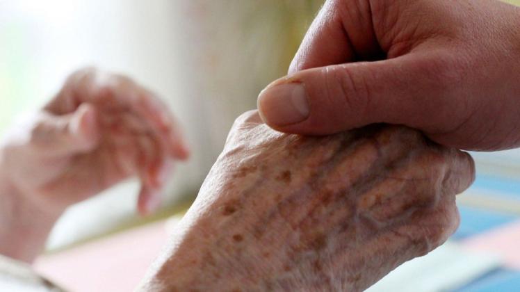 Ein Mitarbeiter eines Alten-und Pflegeheims hält die Hand einer Bewohnerin. Ostholsteins Gleichstellungsbeauftrage wollen die Pflegeberufen stärken.