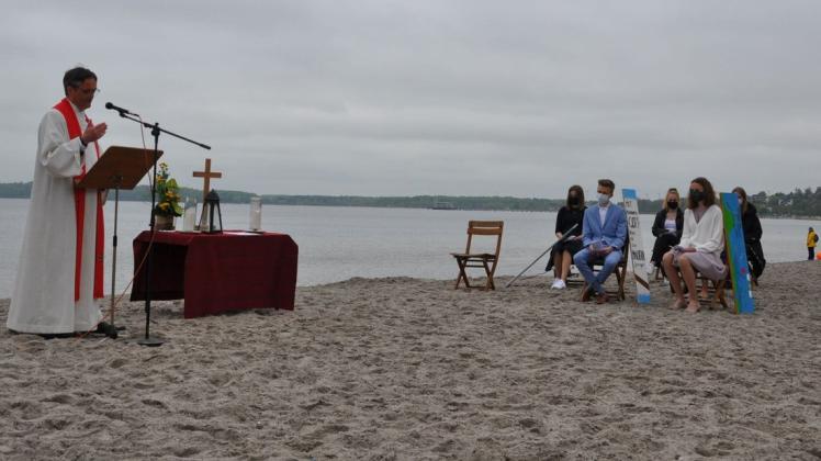 Die Konfirmanden lauschen den Worten von Pastor Michael Jordan. Die Kirchengemeinde St. Nicolai hat ihre diesjährigen Konfirmationen wegen der Corona-Pandemie an den Eckernförder Strand verlegt.