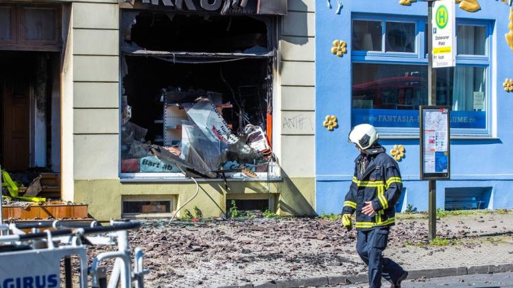 Feuerwehrleute sichern das bei einem Feuer stark beschädigte Wohn- und Geschäftshaus in Rostock.