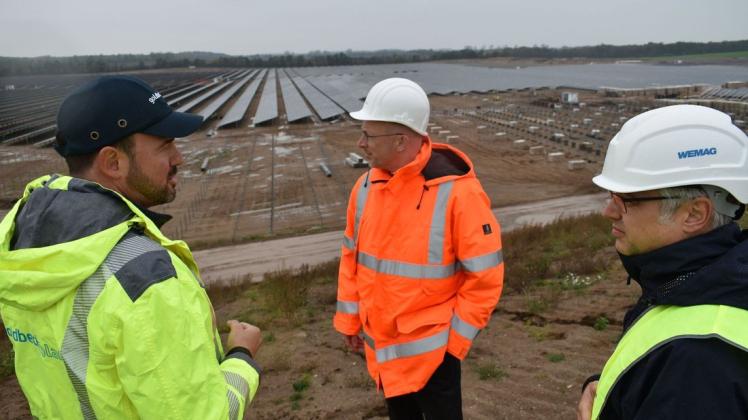 Alexander Gutsch von der Firma Goldbeck Solar, Minister Christian Pegel und Thomas Murche von der Firma Wemag (v. l.) werfen einen Blick auf die Solarmodule.