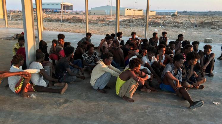 Migranten sitzen an der libyschen Küste etwa 100 Kilometer östlich von Tripolis.