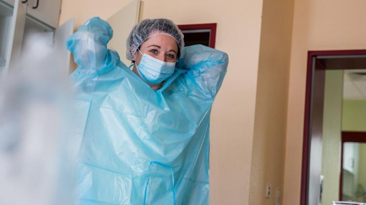 Arbeitet seit 24 Jahren im Crivitzer Krankenhaus: Nancy Strauch zieht sich die Schutzkleidung auf der Coronastation an. Dzazu gehören noch eine FFP2-Maske und ein Visier.