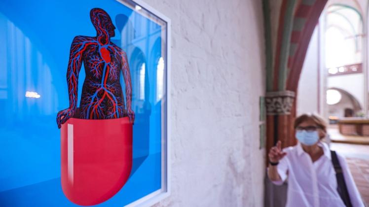 Eine Besucherin betrachtet im Schweriner Dom das Bild ·Die Kapsel· von Alexander Glandien als Teil der Ausstellung "Herzen-Werkstatt".