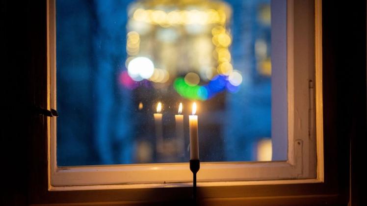 Eine Kerze brennt in einem Fenster als Zeichen des gemeinsamen Gedenkens für die Toten im Zusammenhang mit der Corona-Pandemie.