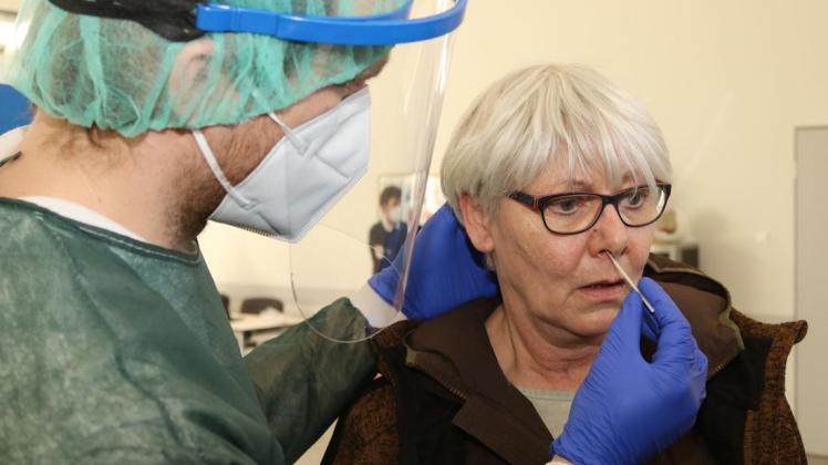 DRK-Kreisbereitschaftsleiter Kai Kuckert führt das Teststäbchen in Astrid Douchys Nasen-Rachen-Raum ein.