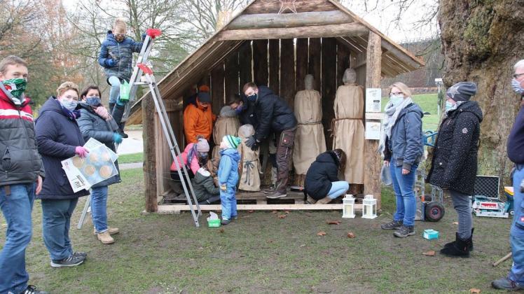 Viele Helfer, jung und alt, haben Freude am gemeinsamen Aufbau einer Außenkrippe im Kurpark Bad Rothenfelde.
