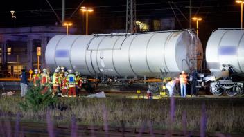 Rettungskräfte und Ermittler stehen neben den abgedeckten Leichen am Kesselwagen.