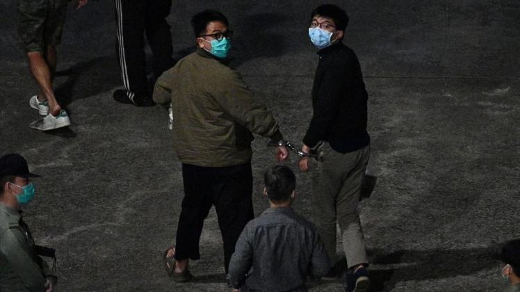 Nach der Urteilsverkündung: Die Aktivisten Ivan Lam und Joshua Wong (r.) bei ihrer Ankunft im Gefängnis, wo sie eine Haftstrafe verbüßen müssen.