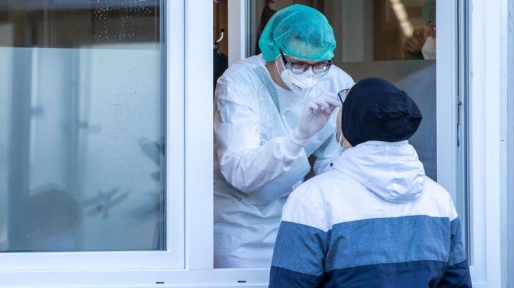 Ein Mitarbeiter nimmt durch ein Fenster im Corona-Testzentrum am Helios-Klinikum einem Mann einen Abstrichtest ab. Seit einigen Tagen arbeitet ein neues Testzentrum direkt am Helios-Klinikum.