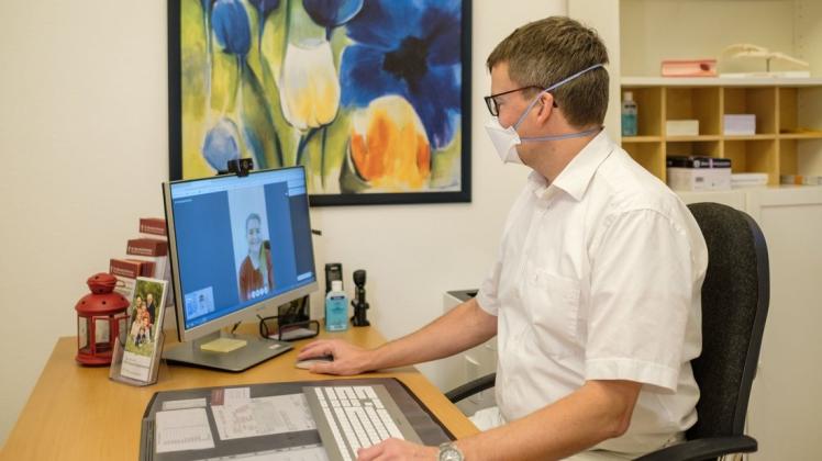 Ein Facharzt für Allgemeinmedizin während einer Online-Sprechstunde am Computer im Behandlungszimmer seiner Praxis. (Symbolbild)