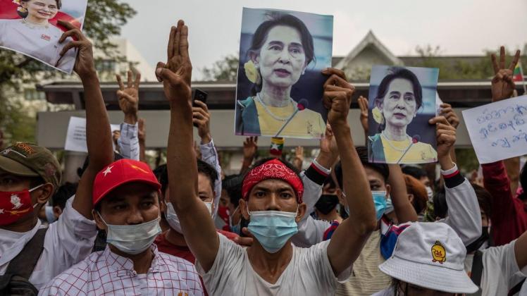 Burmesen und Thais fordern die Freilassung von Aung San Suu Kyi und zeigen das Widerstandssymbol.