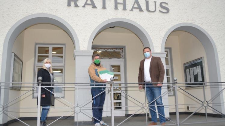 Übergabe mit Corona-Distanz: Petra Lampe und Florian Zimmeck übergeben vor dem Rathaus in Bad Essen einen Stapel mit Unterschriftenlisten an Bürgermeister Timo Natemeyer (rechts).