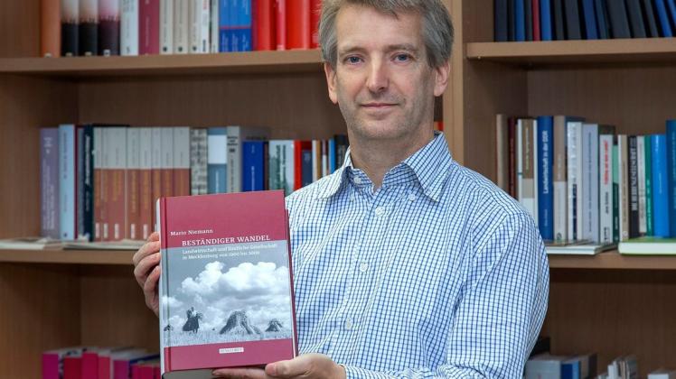 Historiker Mario Niemann zeigt stolz sein Buch mit dem Titel „Beständiger Wandel“.