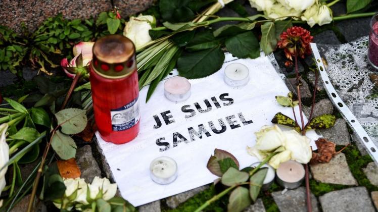 Vor der französischen Botschaft liegen Blumen, Kerzen und ein Blatt mit der Aufschrift "Je suis Samuel". In einem Pariser Vorort wurde der Lehrer Samuel Paty auf der Straße von einem mutmaßlichen Islamisten ermordet.