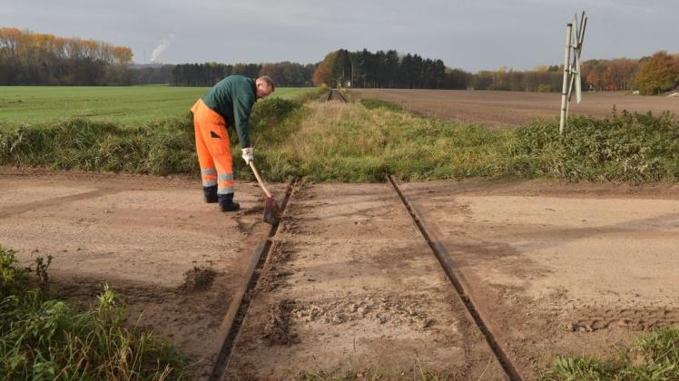 Ein Mitarbeiter der RVM kratzte Montag am Bahnübergang Am Sundern Schlamm aus der Schienenführung. Am Freitag soll ein Zug für baudynamische Messungen über die Gleise rollen.