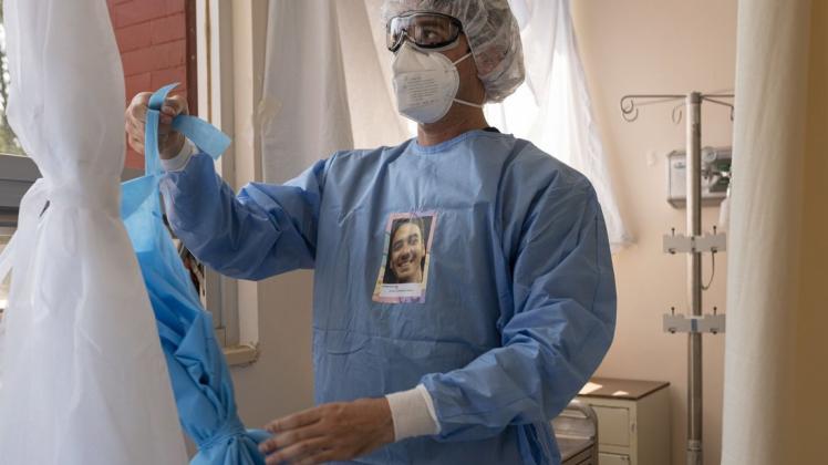 Der Assistenzarzt Alonso Tortoriello trägt Schutzkleidungen mit seinem Porträt in der Fachklinik für Lungen- und Atemwegserkrankungen "INER".