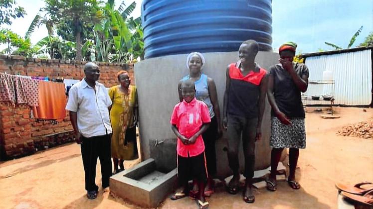 Einer der ersten aufgestellten Wassertanks mit einer Familie aus dem Dorf.