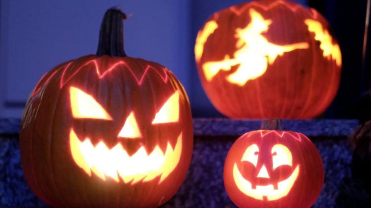 Geschnitzte Halloween-Kürbisse mit Geister-Motiven stehen von innen beleuchtet vor einem Haus. Nach Ansicht zahlreicher Experten sollte Halloween in diesem Jahr wegen möglicher Infektionsgefahr ausfallen.