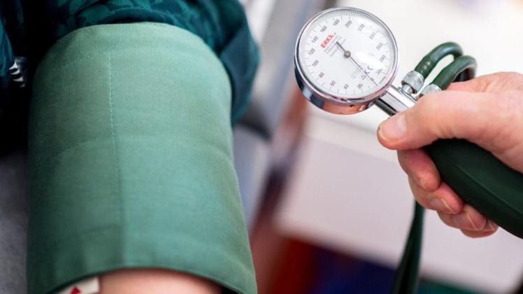 Ein Arzt misst den Blutdruck einer Patientin. Hoher Blutdruck kann auch Folgen für das Herz haben.