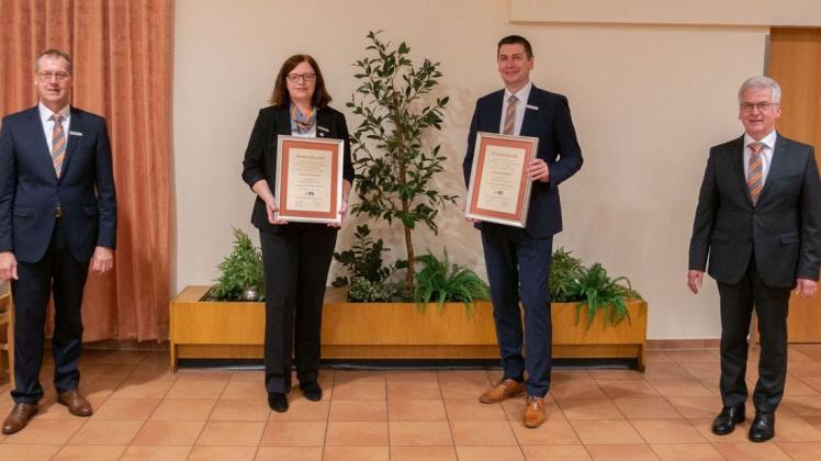 Die Bankvorstände Heinrich Hanekamp (links) und Jürgen Schenzel (rechts) ehrten die Jubilare Karin Pohlabeln und  Jörg Schmalfeldt für ihre jeweils 25-jährige Tätigkeit.