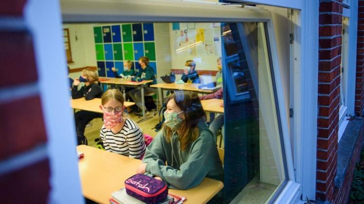 Schülerinnen und Schüler sitzen mit Maske im Unterricht: Ein Bild, das auch in Niedersachsen ab Montag immer häufiger zu sehen sein wird.