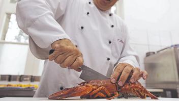 Mit einem scharfen Messer schneidet Chefkoch Carlos Peixoto einen zuvor in Salzwasser gekochten Hummer in zwei Hälften.
