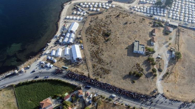 Eine größere Gruppe von Migranten wartet darauf, in das neue provisorische Flüchtlingslager gelassen zu werden.