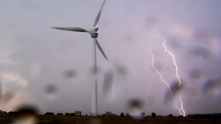 Ein Blitz schlägt Mitte August am Horizont hinter einem Windrad in der Region Hannover ein.