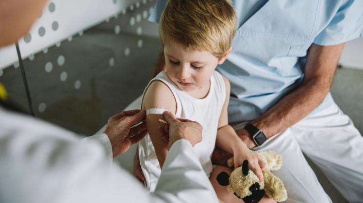 Pediatrist putting band-aid onto arm of toddler after vaccination model released Symbolfoto property released MFF05527